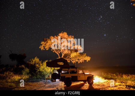 Land Rover garé avec un pop up tente sur son toit sous le ciel nocturne au Botswana, l'Afrique Banque D'Images