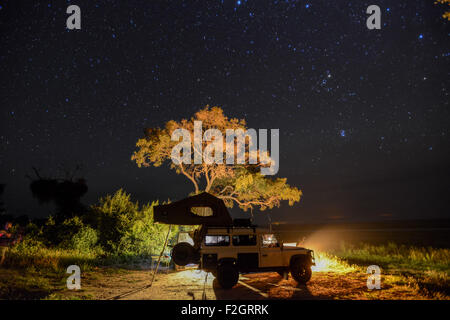 Land Rover garé avec un pop up tente sur son toit sous le ciel nocturne au Botswana, l'Afrique Banque D'Images