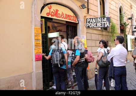 La Foule faisant la queue pour acheter de la nourriture à une petite boutique à Rome. La spécialité, c'est rôti de porc sur un morceau de pain. Banque D'Images