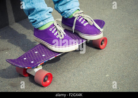 Adolescent pieds de jeans et gumshoes avec skateboard Banque D'Images