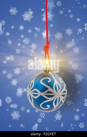 Boule de Noël avec lumière brillante sur l'arrière-plan avec des flocons de neige. Banque D'Images