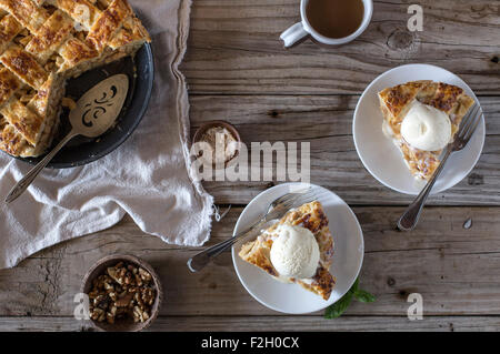 Deux tranches d'une tarte aux pommes au caramel (garnie de crème glacée à la vanille) est affiché sur une table de ferme. Banque D'Images