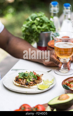 Une poitrine de boeuf mijotés chili taco a servi à une personne dans une table de pique-nique avec de la bière. Banque D'Images