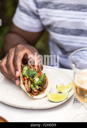 Un homme tient une poitrine de boeuf mijotés chili taco rempli de boeuf haché, le guacamole, les haricots noirs, de la coriandre fraîche et lea Banque D'Images