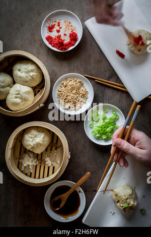 Deux mains de manger des aliments de rue asiatique avec des baguettes en bois de bambou table sur des bateaux à vapeur. Vue d'en haut Banque D'Images