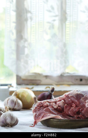 Pain de matières premières d'agneau avec les oignons sur table de cuisine blanche. Avec fenêtre en arrière-plan. Style rustique. Banque D'Images