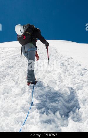 Femme climber ascending une pente enneigée. Banque D'Images