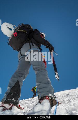 Femme climber ascending une pente enneigée. Banque D'Images