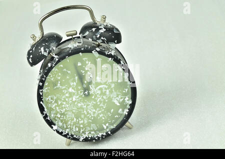 close up of  a snowy black retro alarm clock, showing winter time, 1 am, 2 am, 3 am, with pine cones, horizontal, slanted Banque D'Images