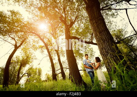 Homme et une femme tenant un bébé dans ses bras dans une forêt d'été à sunny day Banque D'Images