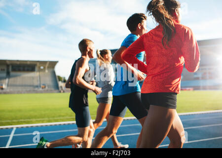 Vue arrière des jeunes exécutant ensemble sur piste de course. Les jeunes athlètes pratiquant un stade d'athlétisme sur piste. Banque D'Images