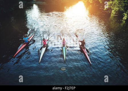 Des personnes de l'équipe d'aviron à l'encontre de caméra dans le coucher du soleil Banque D'Images