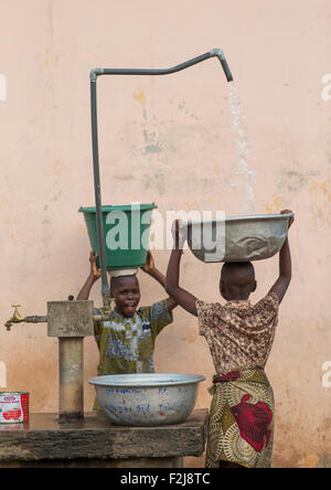 Le Bénin, en Afrique de l'Ouest, Porto-Novo, les enfants vont chercher de l'eau dans la rue Banque D'Images