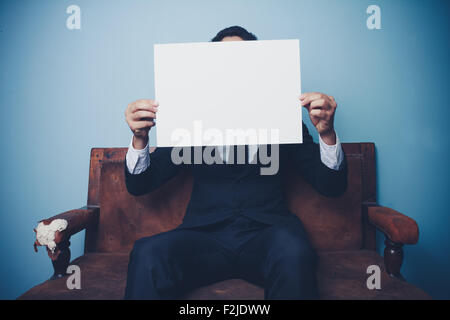 Woman on sofa with white board Banque D'Images