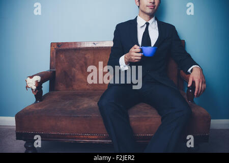 Young businessman sitting on sofa with cocktail Banque D'Images