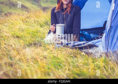 Jeune femme dans la cuisine avec cuisinière portable tente Banque D'Images