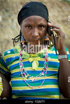 Le Bénin, en Afrique de l'Ouest, Gossoue, une belle femme tribu peul peul tatouée pause avec son téléphone portable Banque D'Images