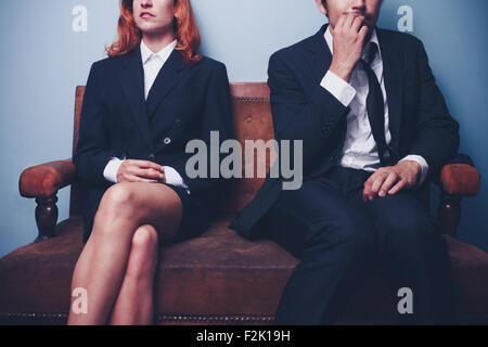 Confident businesswoman et nerveux businessman sitting on sofa Banque D'Images