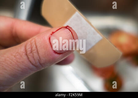 Un pouce qui a été coupé avec du sang autour de la miniature avec un bandage. Banque D'Images