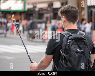 Un homme prend une vidéo selfies avec une caméra GoPro sur un bâton en selfies Times Square à New York. Banque D'Images