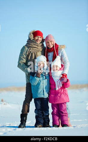 Famille heureuse de quatre en winterwear looking at camera outdoors Banque D'Images