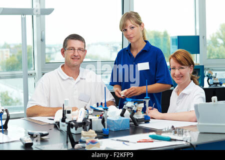 Trois techniciens dentaires travaillant dans un laboratoire dentaire Banque D'Images