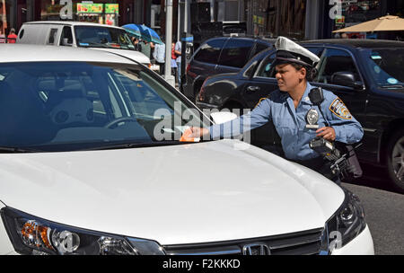 Un agent de la circulation de la ville de New York donne un billet pour un véhicule arrêté à un mètre a expiré. Dans la région de Jackson Heights, Queens, New York Banque D'Images