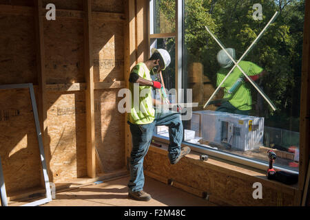 Travailleur installe Windows sur nouveau terrain High School bâtiment LEED Platine. Banque D'Images