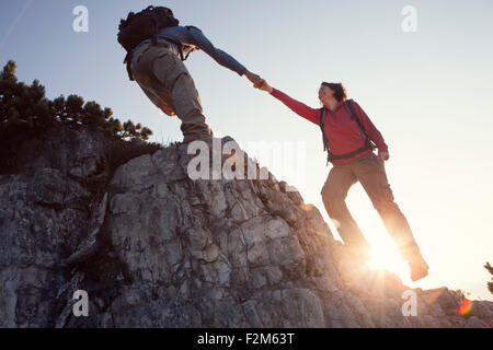 Autriche, Tyrol, Unterberghorn, man helping woman sur voyage randonnée Banque D'Images