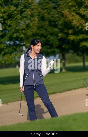 Golfeuse motivés faisant un geste de main de réussite et de jubilation après avoir joué son coup pour sortir d'un bunker de sable sur une Banque D'Images