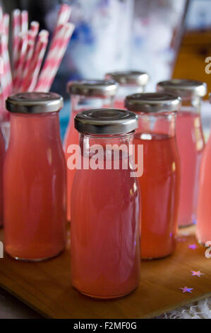 Close up vertical des bouteilles de limonade rose rose avec des pailles. Banque D'Images