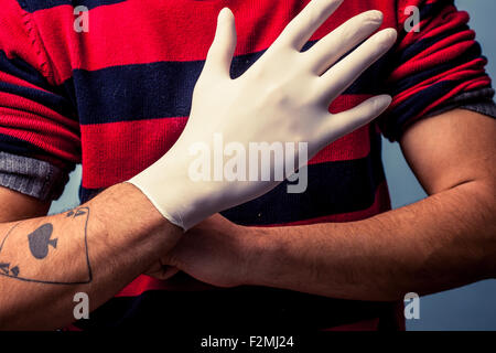 Man putting on rubber glove Banque D'Images