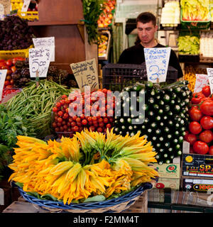 Vendeur à l'erbaria (marché aux légumes) Rialto, Venise, Italie. Un panier de fleurs de courgettes, tomates, haricots, courgettes et en vente Banque D'Images