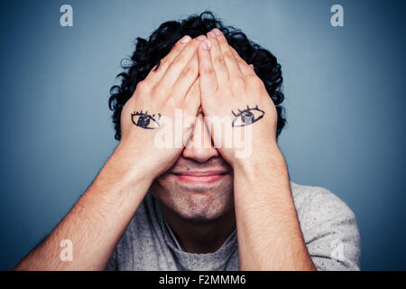 Jeune homme avec les yeux peints sur les mains Banque D'Images