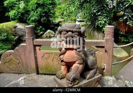 Le Ping, ville ancienne, Chine : une statue de grès rose Fu Dog donne sur les plantations luxuriantes et un ruisseau Banque D'Images