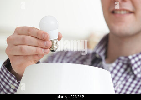 Man Putting Low Energy ampoule LED en voyant à l'accueil Banque D'Images