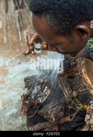 Le Bénin, en Afrique de l'Ouest, Bopa, batteur de cracher l'alcool sur un tambour pour réveiller son esprit avant qu'une cérémonie vaudou Banque D'Images