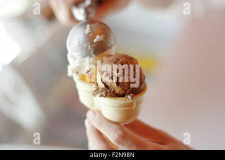 L'écopage la crème glacée dans des cônes Banque D'Images