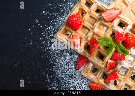 Gaufres avec quelques fraises fraîches (détaillées close-up shot) sur fond sombre Banque D'Images