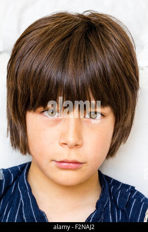 Caucasien enfant, garçon, 10-11 ans. Les cheveux bruns, tête et épaules, en face avec le contact avec les yeux, regardant viewer. Agacé, l'expression de défi. Banque D'Images