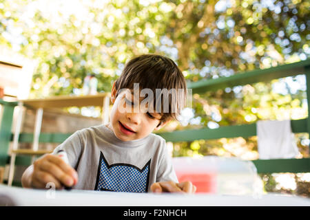 Mixed Race boy coloring on porch Banque D'Images
