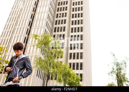 Asian man standing près de gratte-ciel urbain Banque D'Images