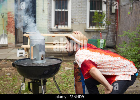 Caucasian man lighting pour charbon grill in backyard Banque D'Images