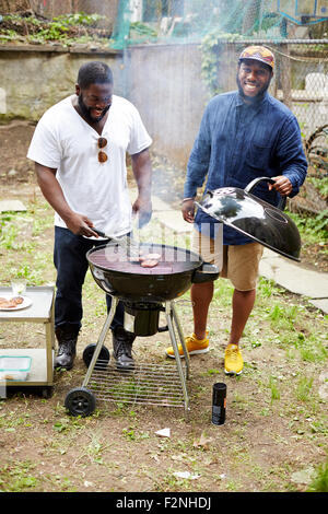 Les hommes noirs des hamburgers dans un barbecue cuisson Banque D'Images