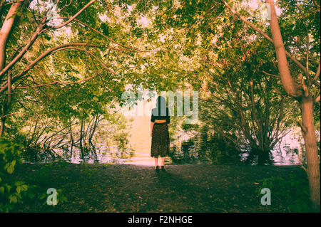 Portrait femme debout sous les arbres près de la rivière Banque D'Images