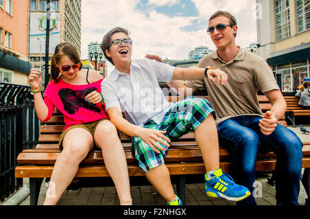 Caucasian friends jouant sur banc de la ville Banque D'Images