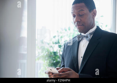 Groom in tuxedo using cell phone Banque D'Images