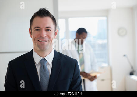 Businessman smiling in office avec médecin Banque D'Images