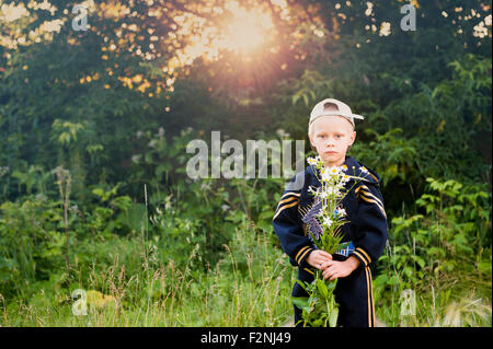 Caucasian boy Picking Flowers in rural field Banque D'Images