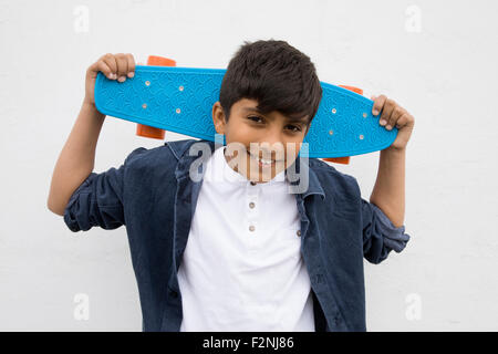 Asian boy holding skateboard Banque D'Images